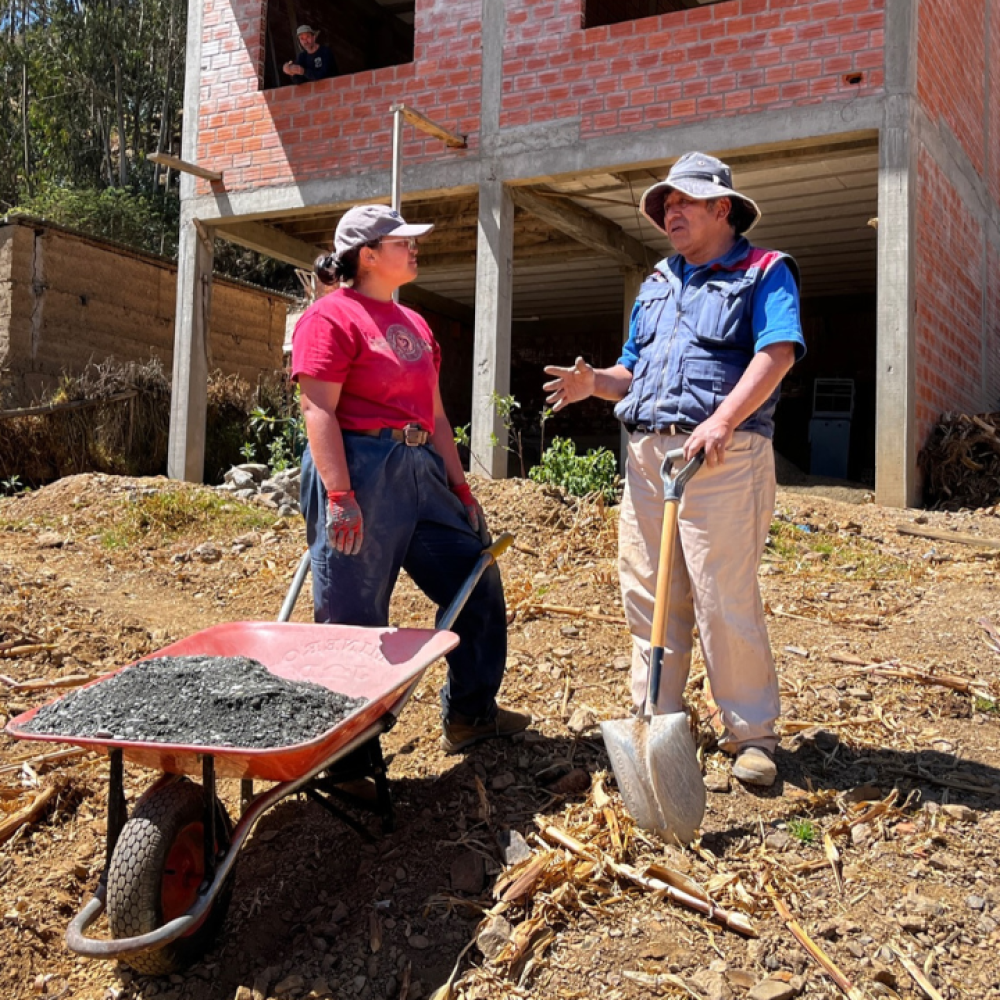 People stand on construction site with wheel barrow