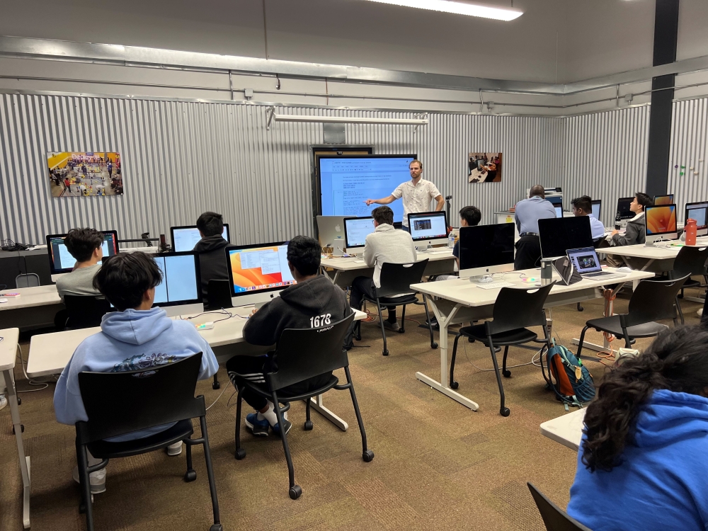 A teacher leads a classroom of young students working on computers