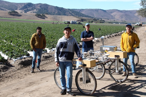 Rajkishan Arikapudi and Peng Chen, Professor Stavros Vougioukas and postdoctoral scholar Zhenghao Fei stand in strawberry field next to cart