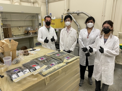Four people in La Saponara's lab pose for a group photo near samples of bamboo, mycelium and biomass