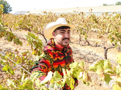 Jesus Trujillo wearing a cowboy had and standing on his family's crop field