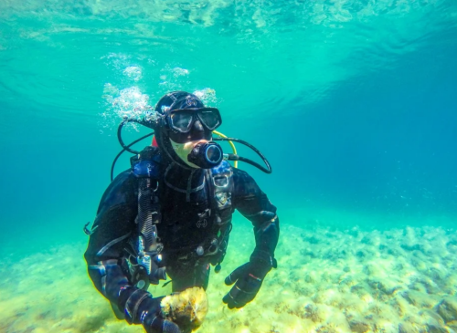 Brandon Berry under water in diving gear near algae growth, holding a specimen