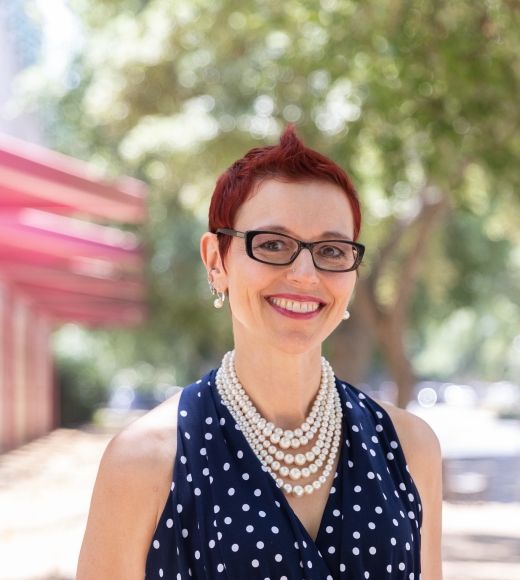 Lisa Laughter standing outdoors, wearing a pearl necklace and polka dot shirt