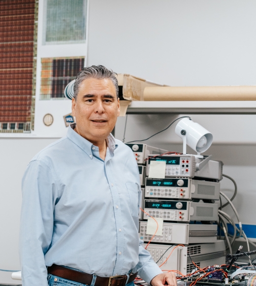 Bevan Bass poses in front of equipment at his VLSI Lab in Kemper Hall.