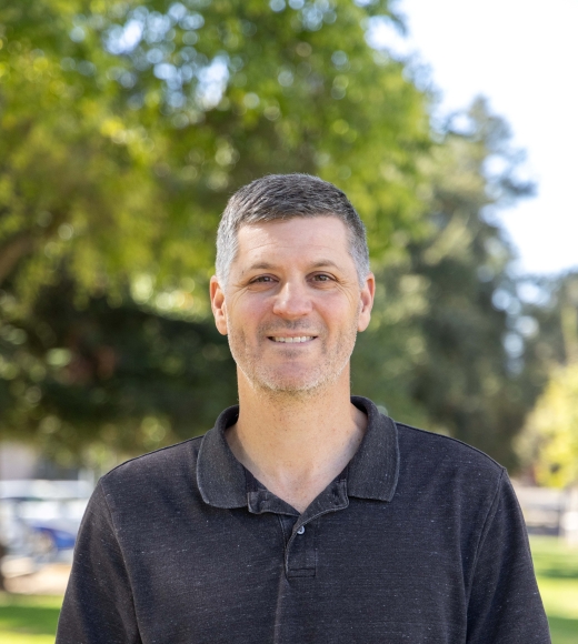 Associate Professor of Computer Science Sam King wearing a black polo shirt in front of a natural background