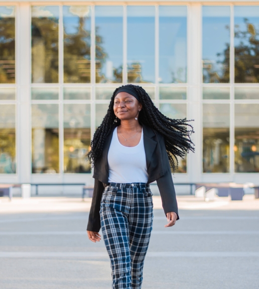 UC Davis Student Xaviera Azodoh walking outdoors with her hair swinging and one leg in front of the other