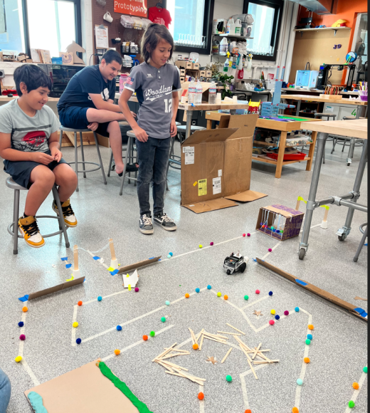 Students in room with maze for robots made out of small wood pieces