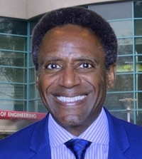 Middle-aged Black man in a blue suit in front of Kemper Hall