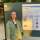 Ekaterina stands next to poster