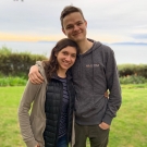 Caleb Stanford with his wife Ariana standing on green grass near a coastline