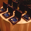 Boxes with medals inside sit on a circular table at a celebration event