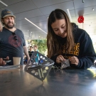 Three people spinning metal tops