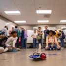 A crowd watching a small robotic car