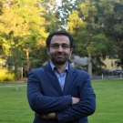 Amir Saeidi standing outdoors near green grass and trees