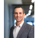 Ben Serna in a gray blazer, with a blurred office background.