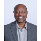Dr. Bruce Mansell in a gray blazer and light shirt against a light background.