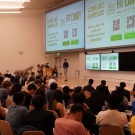 A student presents on stage in front of a full audience