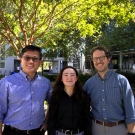 Three people stand together outdoors