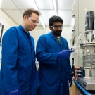 Two students in blue uniforms handling lab equiptment