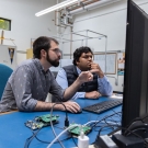 UC Davis graduate students Adam Zufall and Ayush Patnaik sit at a desk working on a payload
