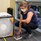 A woman squatting near a large air cleaner