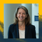 Rebecca Richards-Kortum: Smiling woman with long hair in a dark blazer and white shirt stands indoors against a yellow and dark blue abstract background.