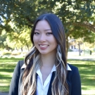 Roanna Pham in blazer headshot photo outdoors with sunlit leafy background