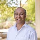 Sen in white shirt with blurred trees in background