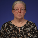 A professor speaking passionately on a purple backdrop
