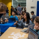Student start up teams from UC Davis Engineering sit at tables in the Engineering Student Design Center and talk with event goers for the grand opening