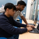 Ashwin Chembu and Gautham Pandian indoors working on a laptop