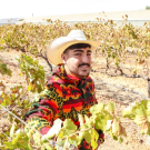 Jesus Trujillo wearing a cowboy had and standing on his family's crop field