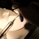 Mingwei Zhang working in a dark room with light on work table, zoomed in to what he is working on