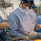 Surgical team in blue scrubs and masks operating on a patient in an OR