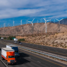Highway with cars and trucks and hills with wind turbines