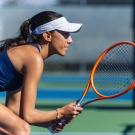Kaia Wolfe crouching with a tennis racket